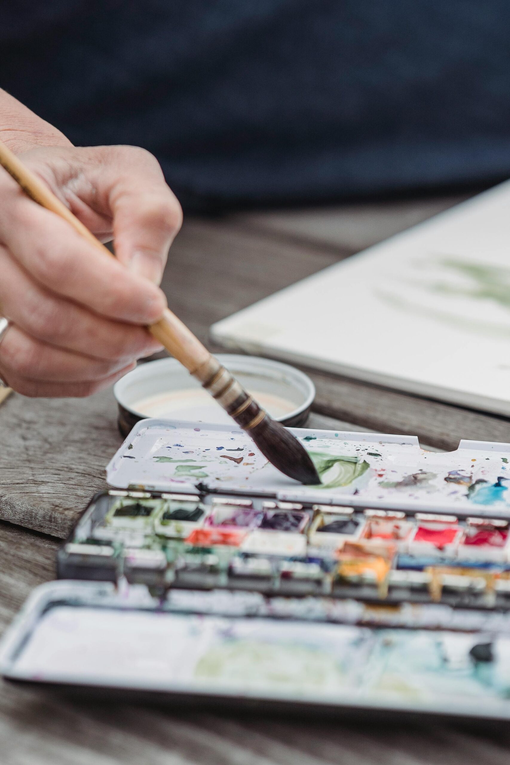 Close-up of a hand using a paintbrush to apply watercolor to paper. Perfect for creative and artistic concepts.